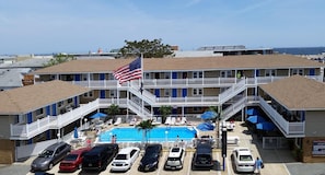 Un motel con piscina, varios balcones y una bandera.