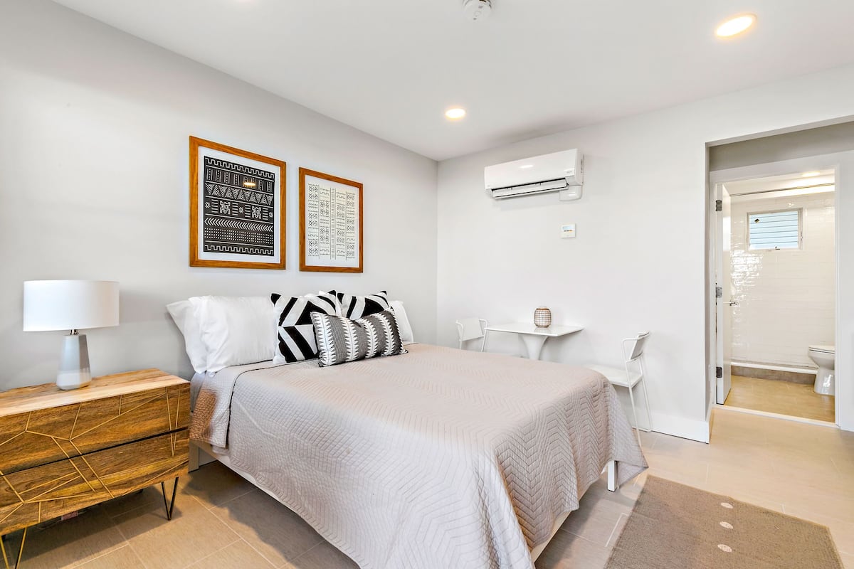 A modern bedroom with a bed, bedside table, and a small desk.
