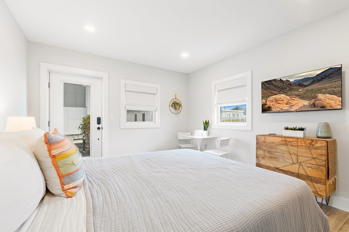 A bedroom with a bed, a desk, a chair, a dresser, and a painting on the wall.