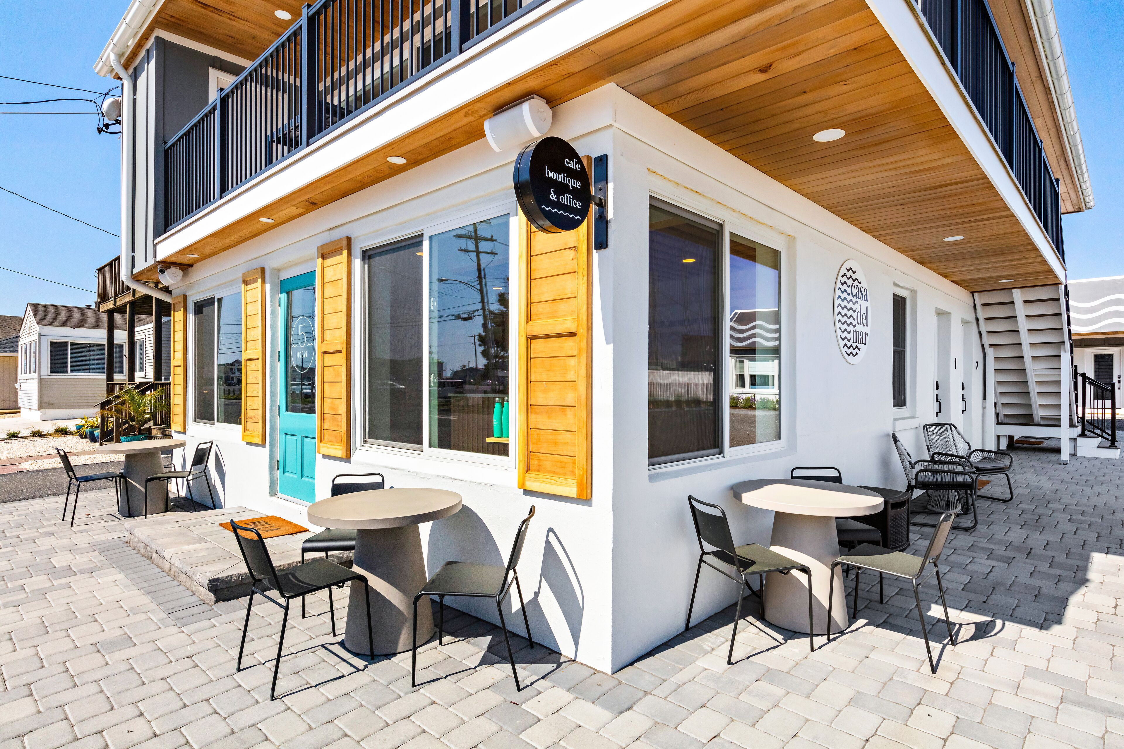 A cafe with outdoor seating, wooden shutters, and a sign indicating it is a boutique and office.