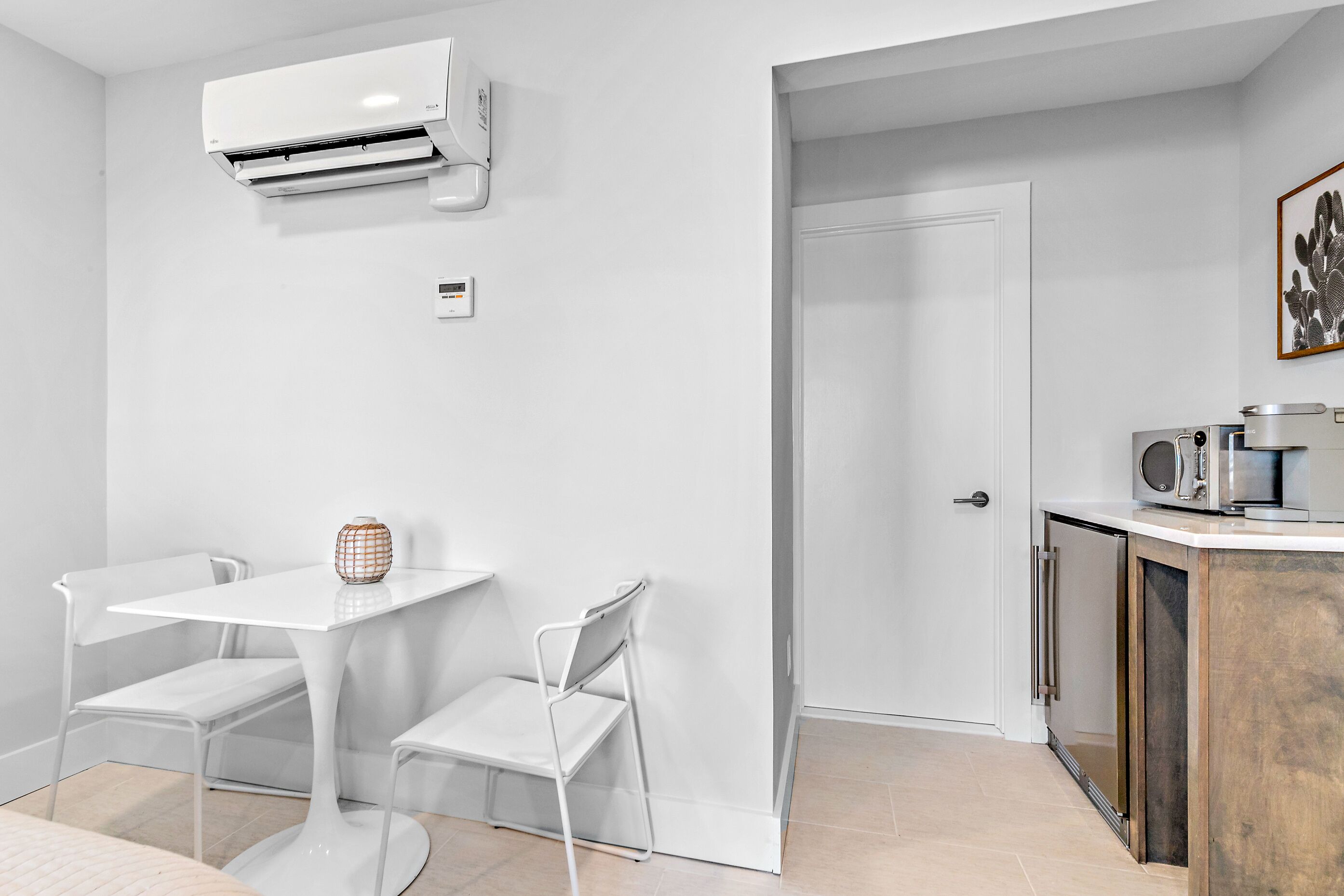 Una cocina moderna con armarios blancos, microondas integrado y una mesa blanca con sillas.