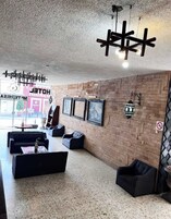 Un vestíbulo con pared de ladrillo, sofás negros, una mesa redonda y cuadros enmarcados.