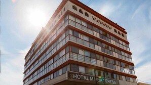 Un edificio de hotel de varios pisos con un cartel que dice 'HOTEL MARIA TERESA'.