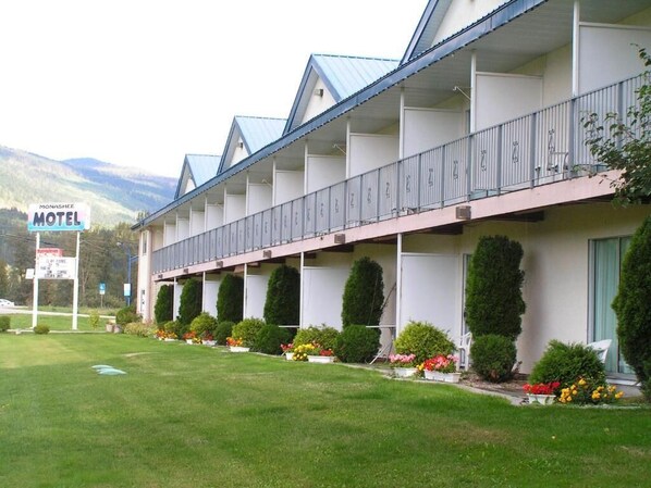 A motel with a row of rooms, each with a balcony. - Monashee Motel (Sicamous)