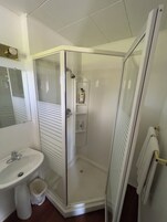 Un baño con ducha de vidrio, lavabo y espejo.
