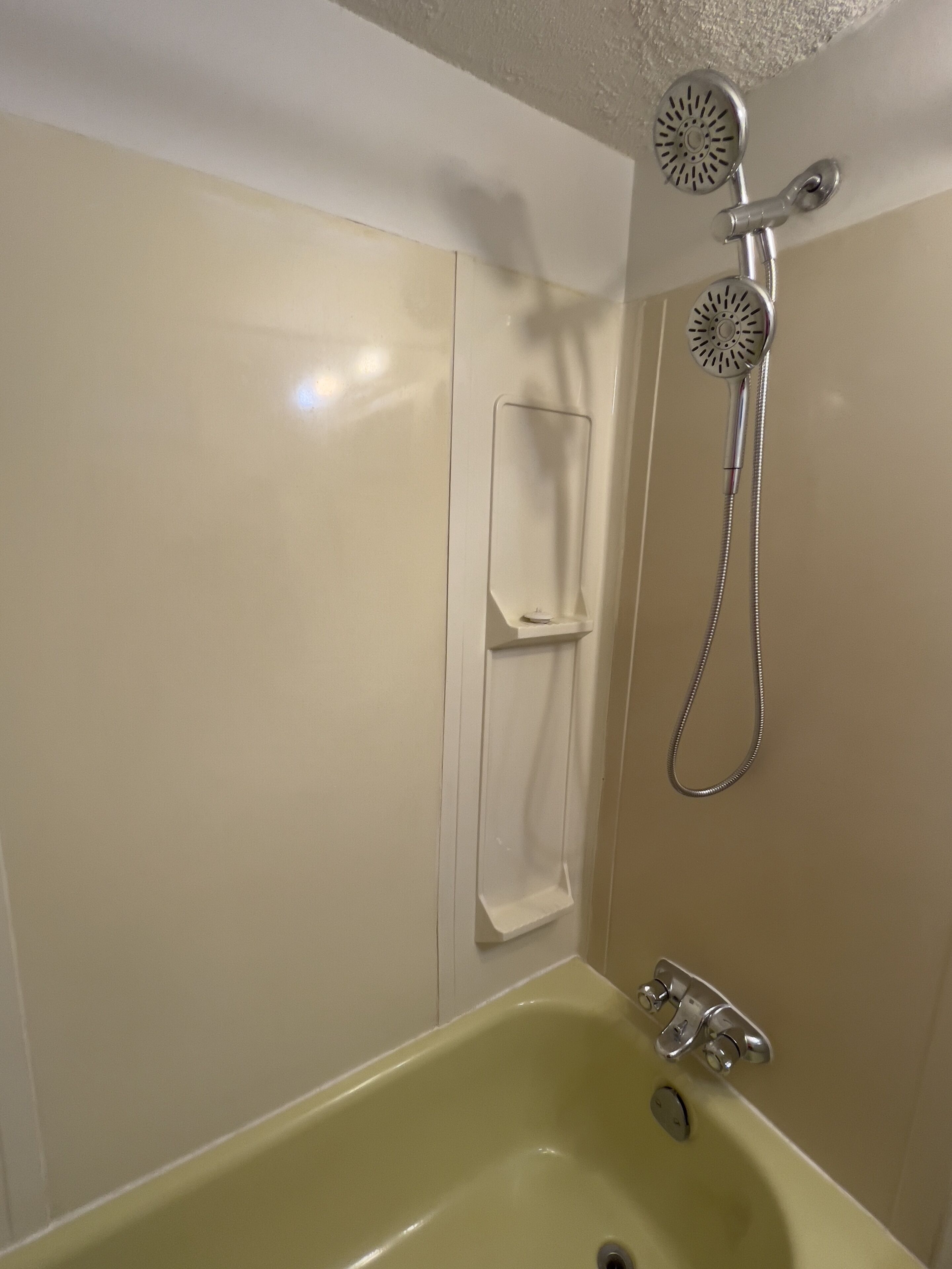 A bathroom with a bathtub, a showerhead, and a towel rack.