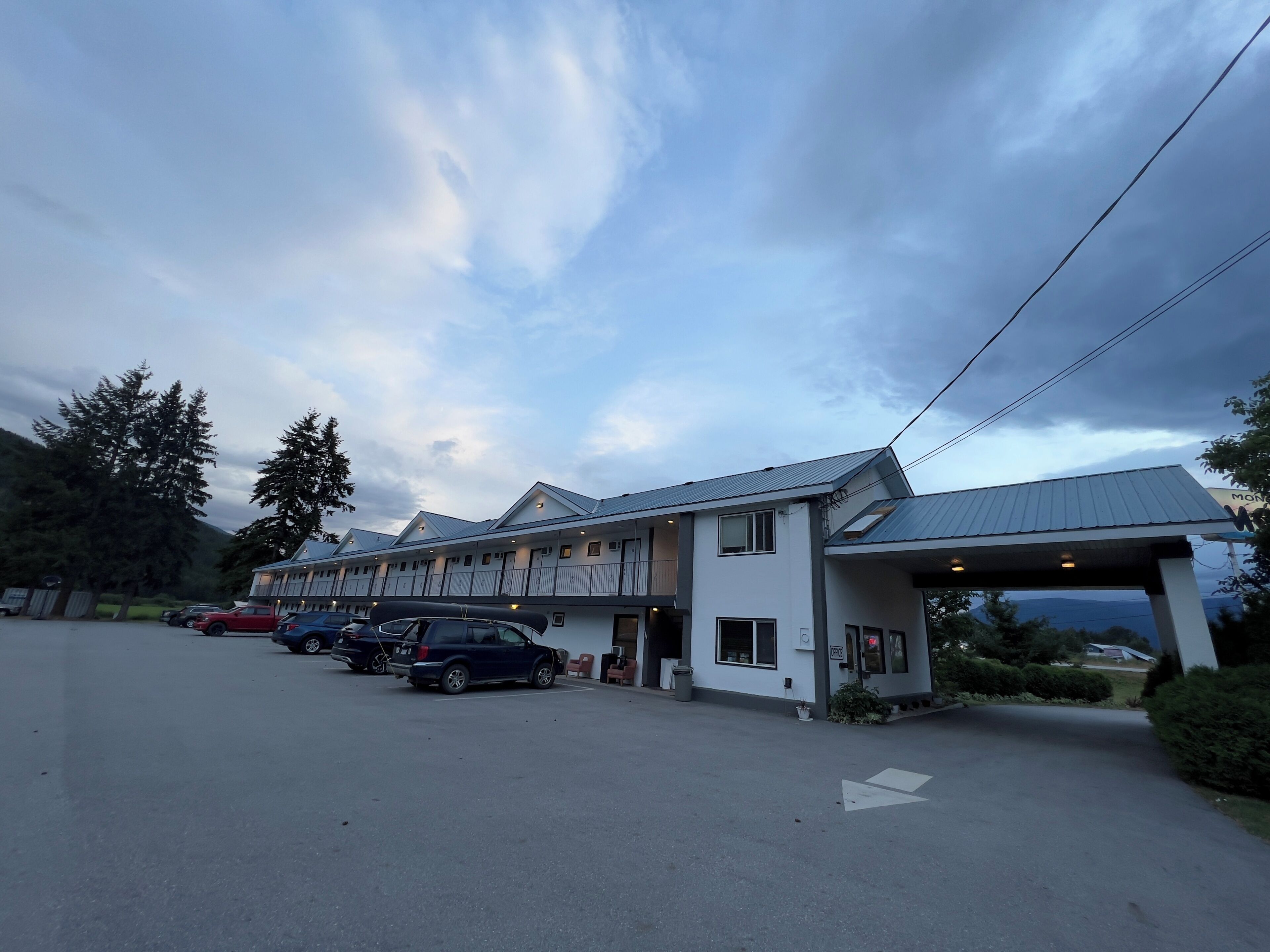 A motel with a parking lot, a covered entrance, and a mountain view.