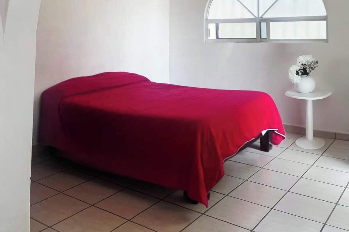 Ein Schlafzimmer mit Bett, Deckenventilator, Fenster und einem Gemälde.