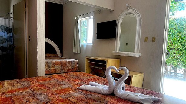 Une chambre d’hôtel avec un lit, un bureau, un miroir et une télévision.