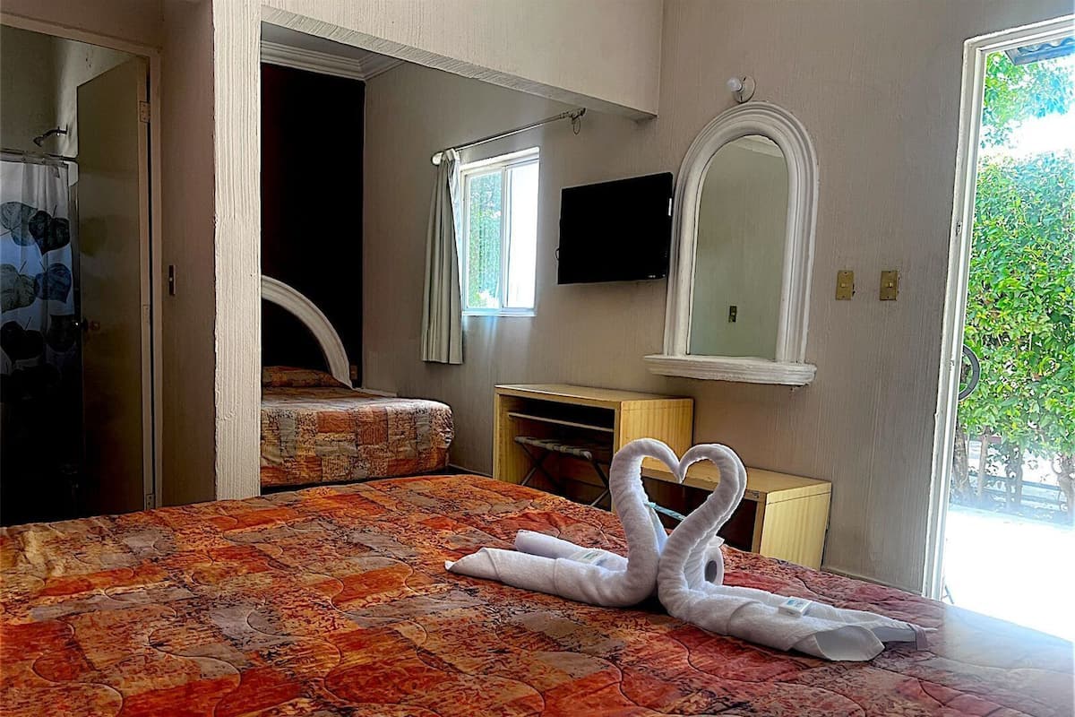 Ein Hotelzimmer mit einem Bett, einem Schreibtisch, einem Spiegel und einem Fernseher.