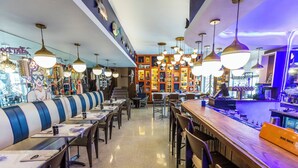 A restaurant with booths and tables, a bar area, and a wall with various items and decorations. - Oceanside Hotel and Suites (Miami Beach)