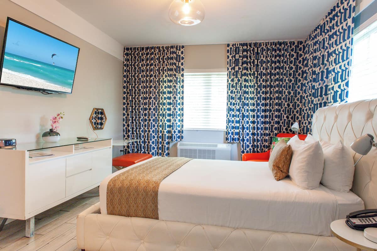 Une chambre d’hôtel moderne dotée d’un grand lit, d’un téléviseur à écran plat, d’un bureau et de rideaux à motifs.