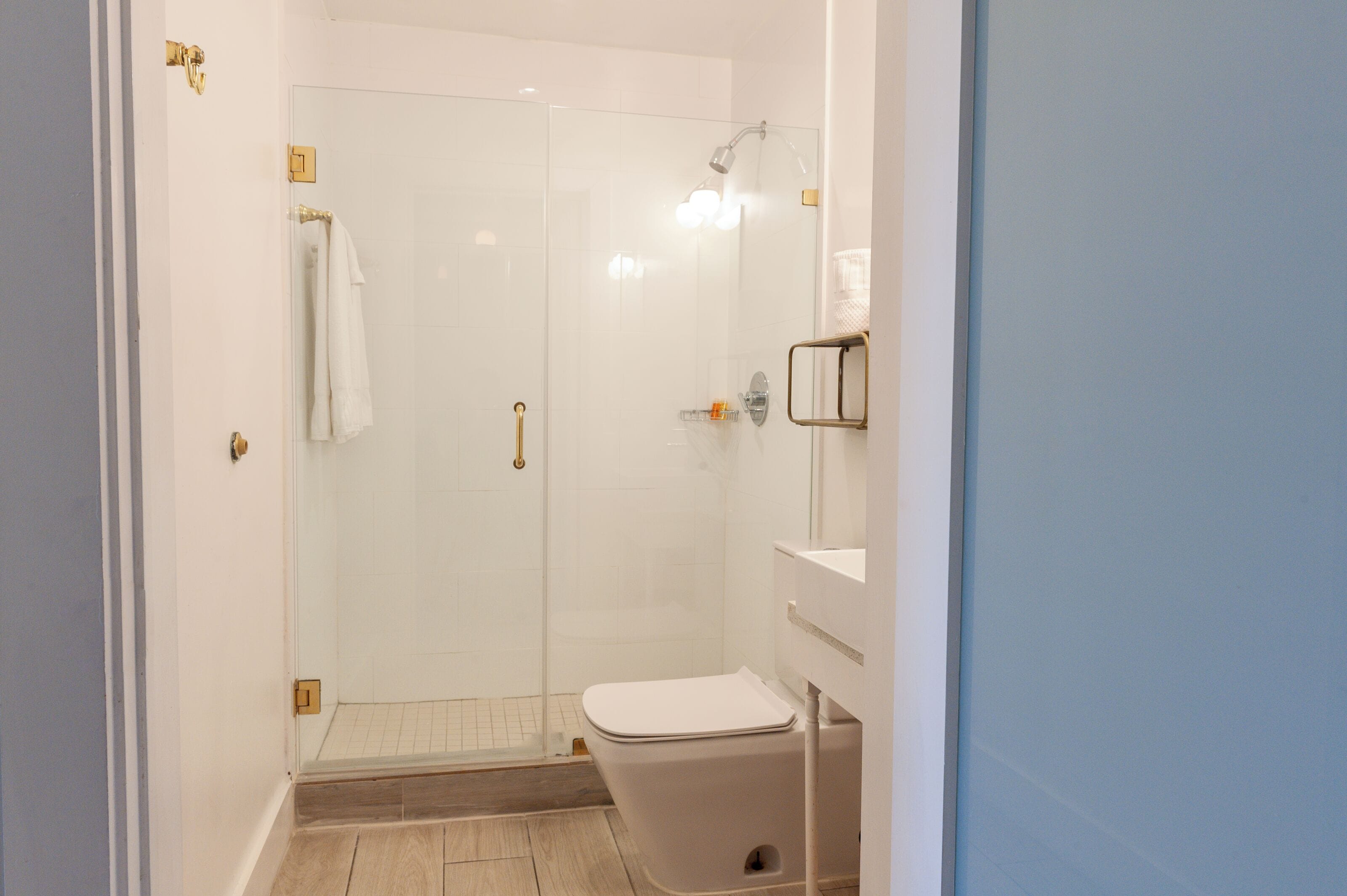Ein Badezimmer mit Duschkabine, Toilette und Waschbecken mit Spiegel.