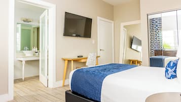Une chambre d’hôtel équipée d’un lit, d’un bureau, d’une télévision et d’une salle de bain avec un miroir et un lavabo.
