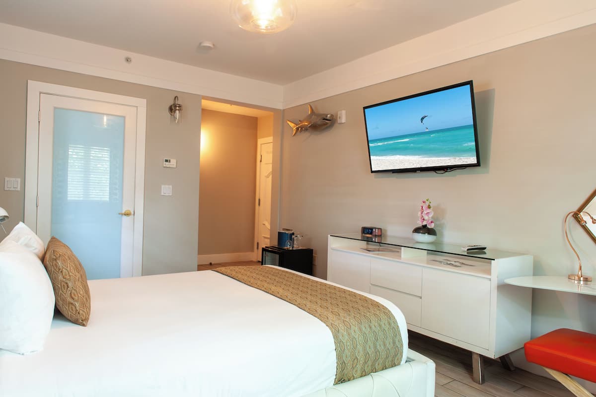 Une chambre d’hôtel avec un lit, un bureau, une télévision et une porte.