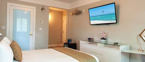 A hotel room with a bed, a desk, a television, and a door.