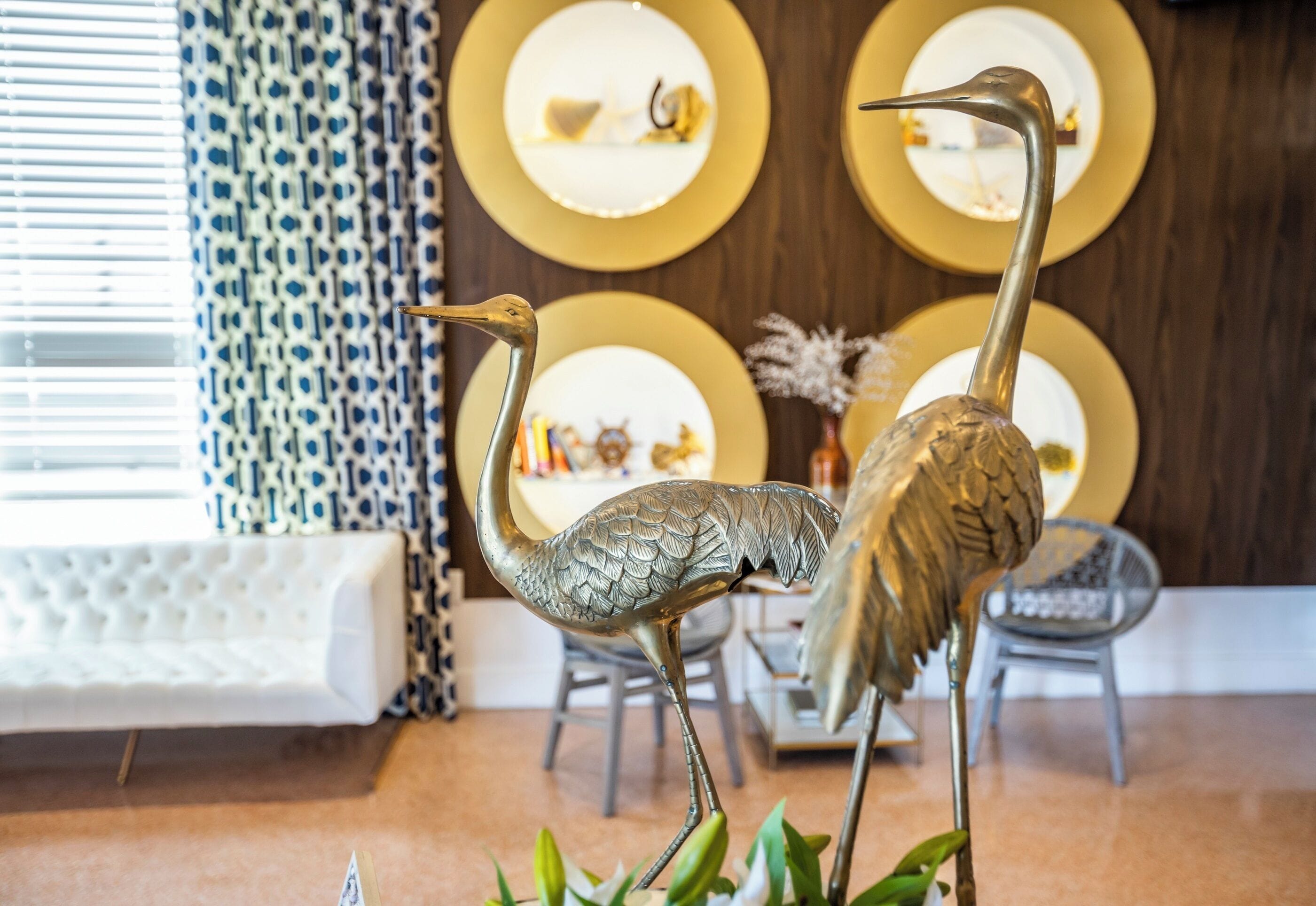 A room with a white sofa, a patterned curtain, and a wall with circular gold plates.