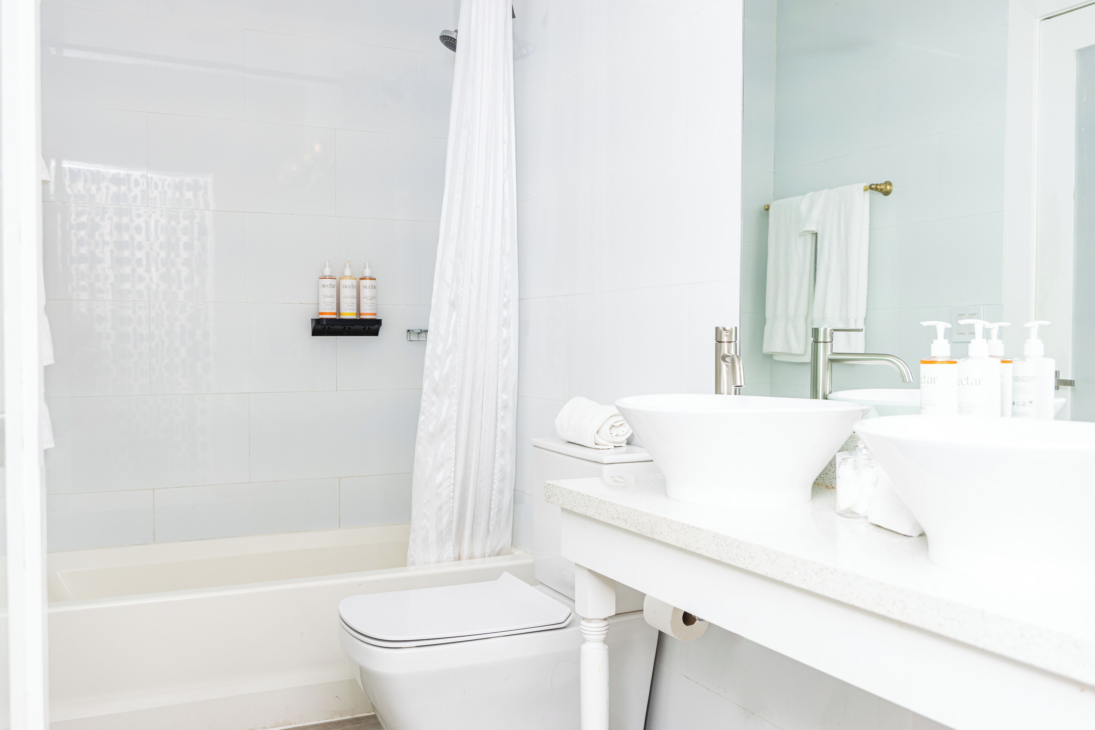 Ein modernes Badezimmer mit Badewanne, Toilette und Waschtisch inklusive Spiegel und Waschbecken.