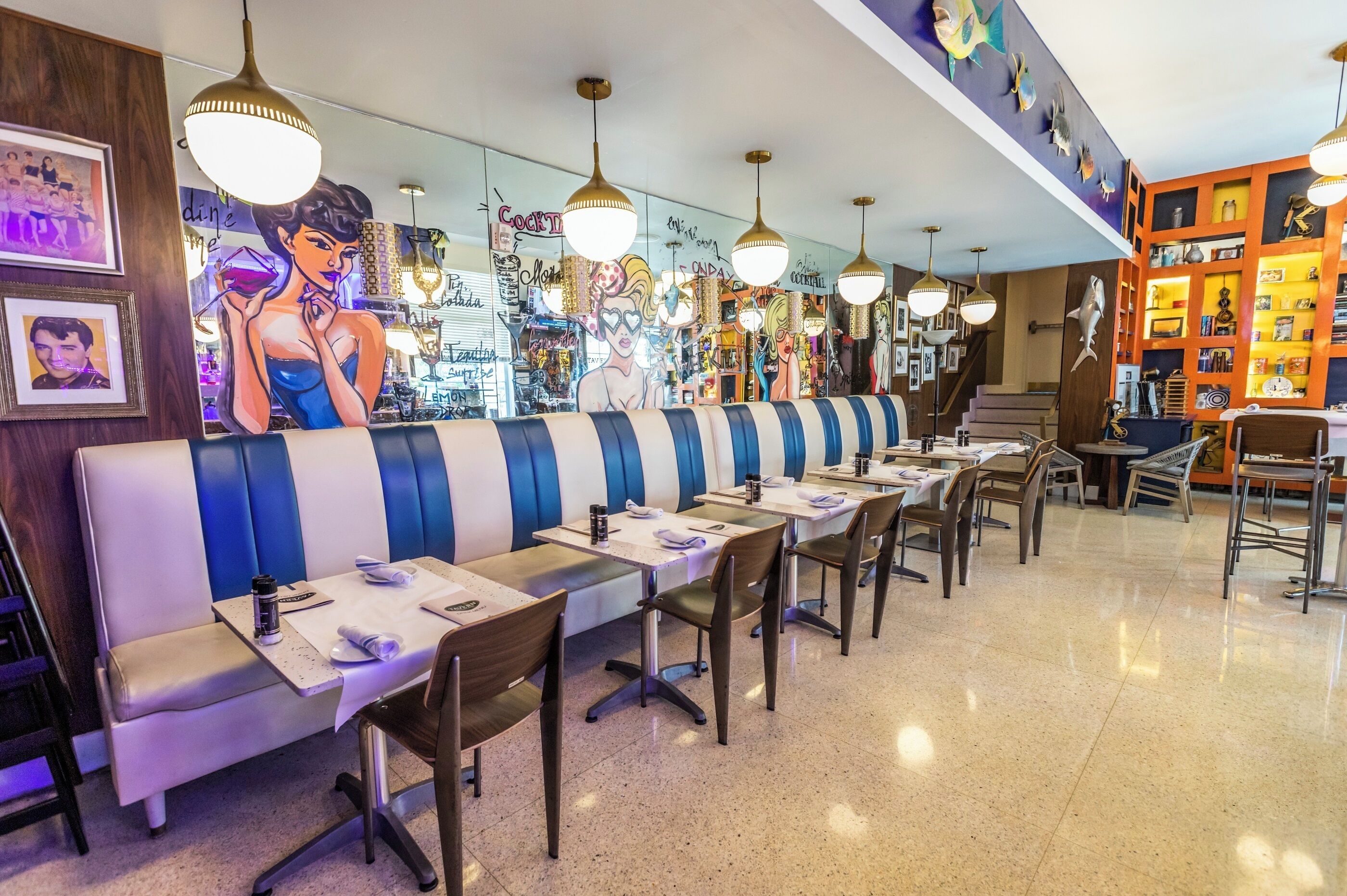 A restaurant with a long counter, striped booth seating, and hanging pendant lights.