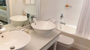 Ein Badezimmer mit zwei Waschbecken, einem Spiegel, einer Toilette und einer Badewanne.