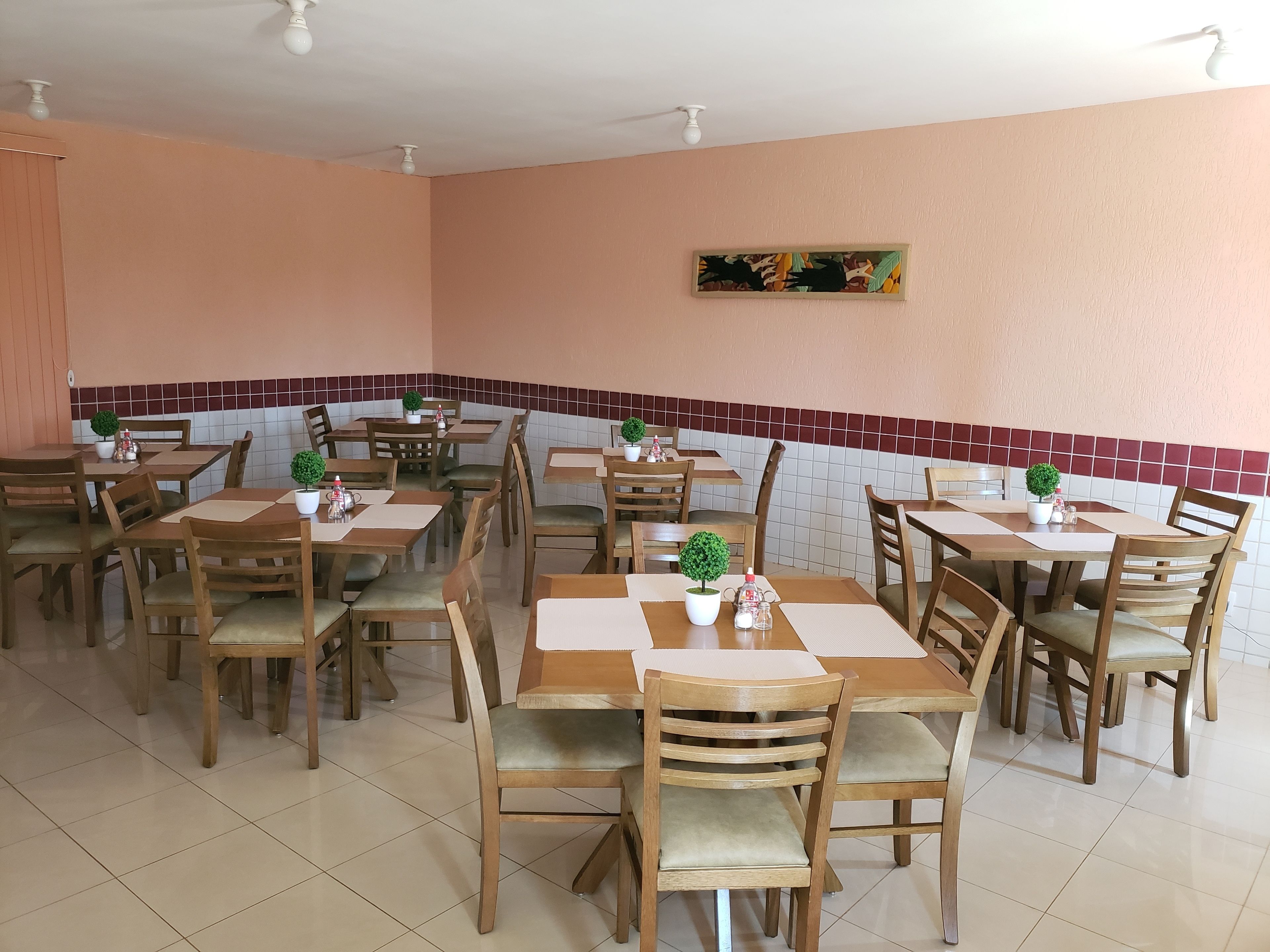 Un restaurante con mesas y sillas de madera, paredes de azulejos y ventiladores de techo.