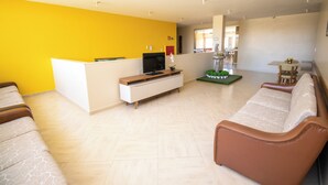 Un salon avec un canapé, un téléviseur et une petite table sur laquelle est posée une plante.