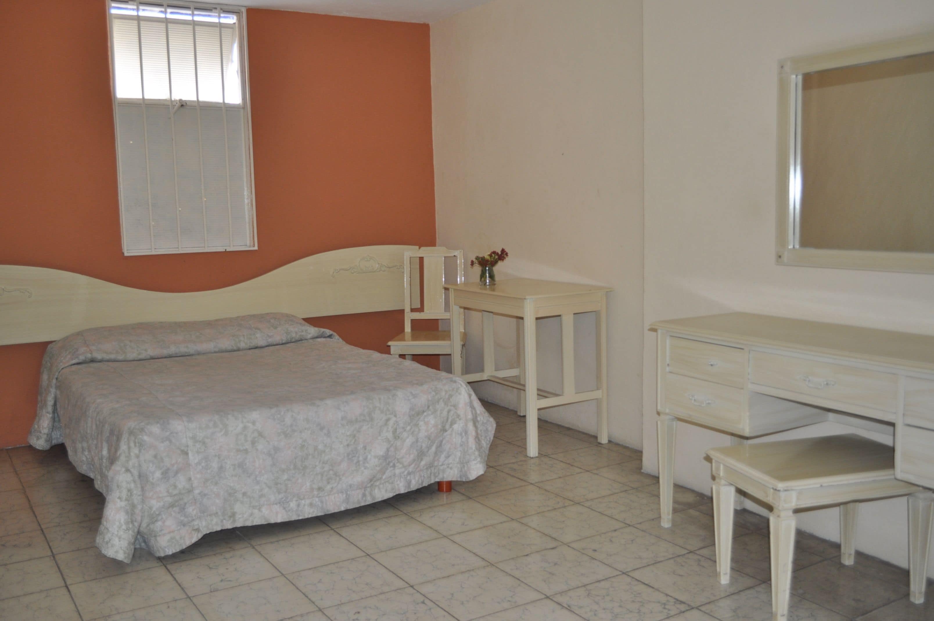 Un dormitorio con una cama, un escritorio y una silla.