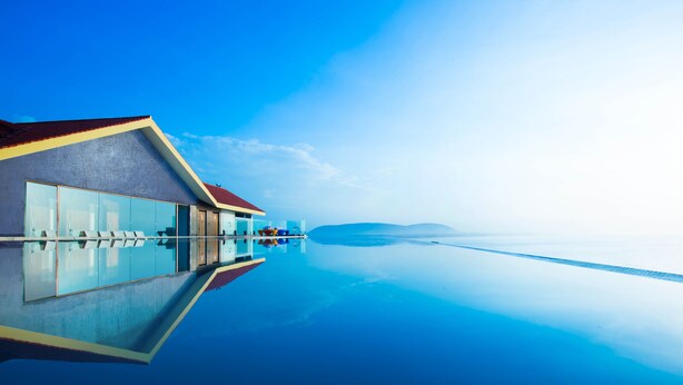 A modern hotel with a glass infinity pool, a red roof, and a clear view of the horizon. - The Bheemli Resort - Managed by AccorHotels (Bhimunipatnam)
