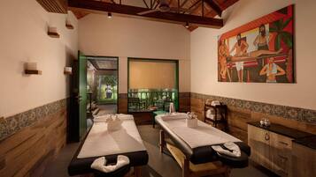 A room with two massage tables, a painting, and a view of the outdoors.