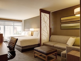 Habitación de hotel con dos camas, un sofá, un escritorio y una silla.