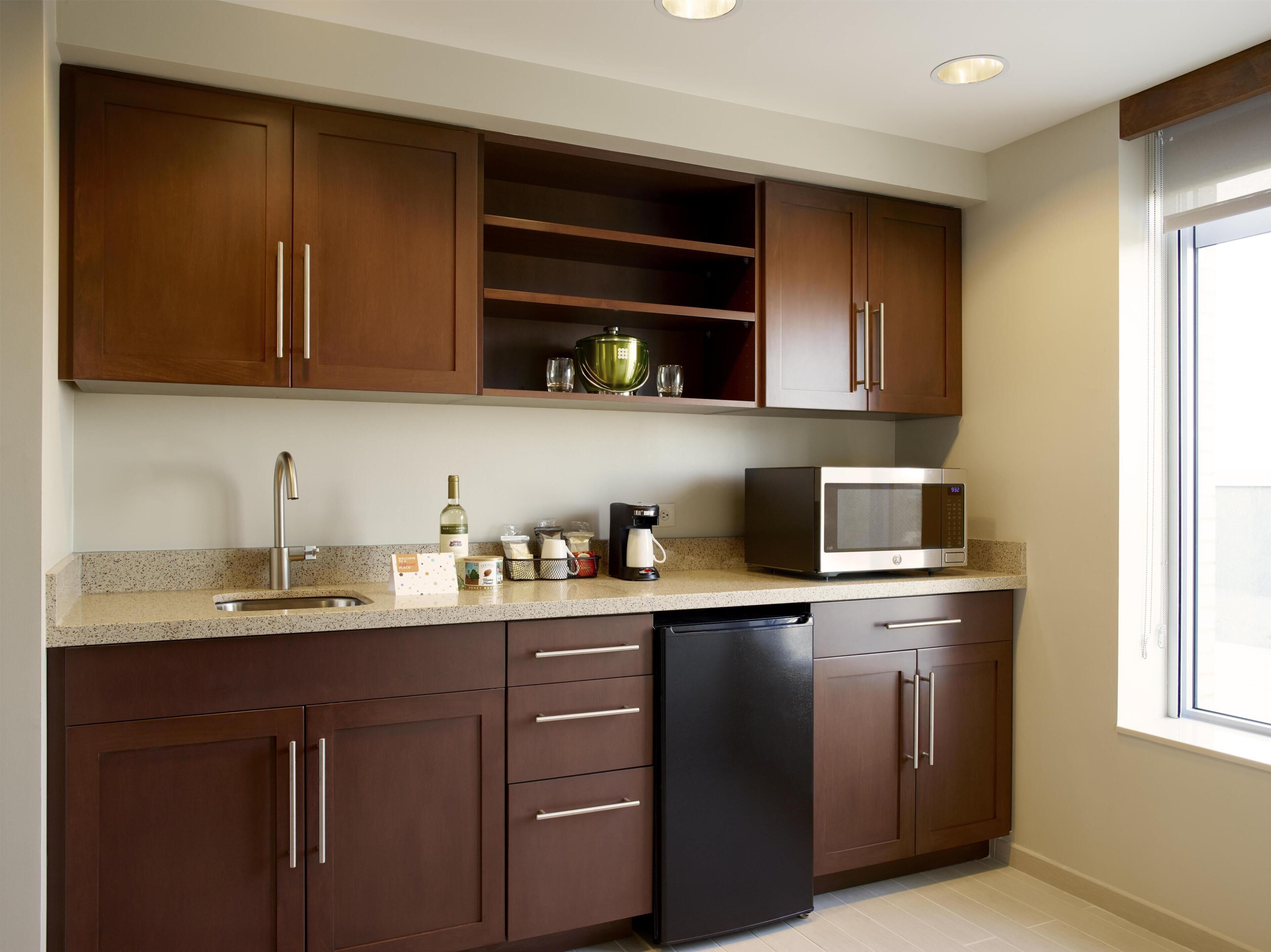 Cocina con armarios de madera, un lavamanos de acero inoxidable, un microondas y un lavavajillas.