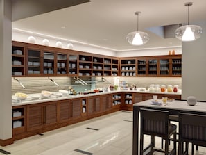 A modern kitchen with wooden cabinets, a breakfast bar, and pendant lighting. - Hyatt Place Arlington/Courthouse Plaza (Arlington)