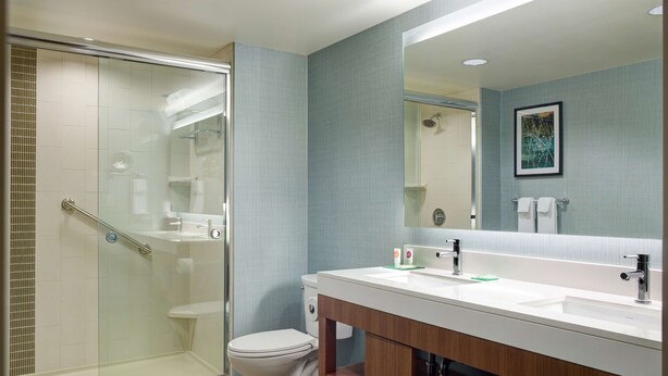 Une salle de bain moderne avec une douche à parois de verre, des toilettes blanches et un meuble-lavabo avec un miroir.