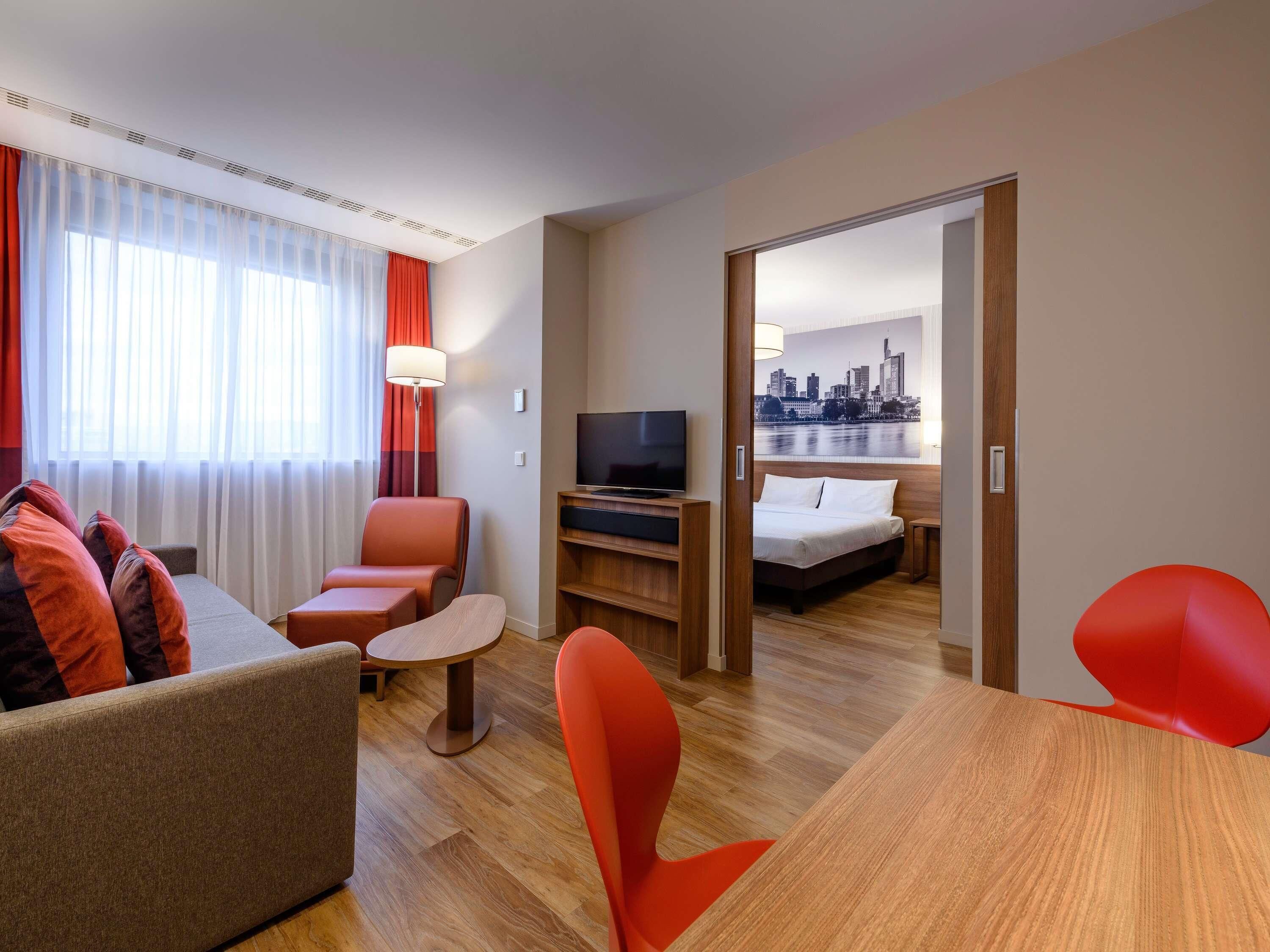 Une chambre d’hôtel avec un canapé, un fauteuil, une télévision et un lit.