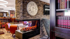 Un interior moderno con una chimenea de piedra, un reloj de pared grande y una estantería llena de libros.