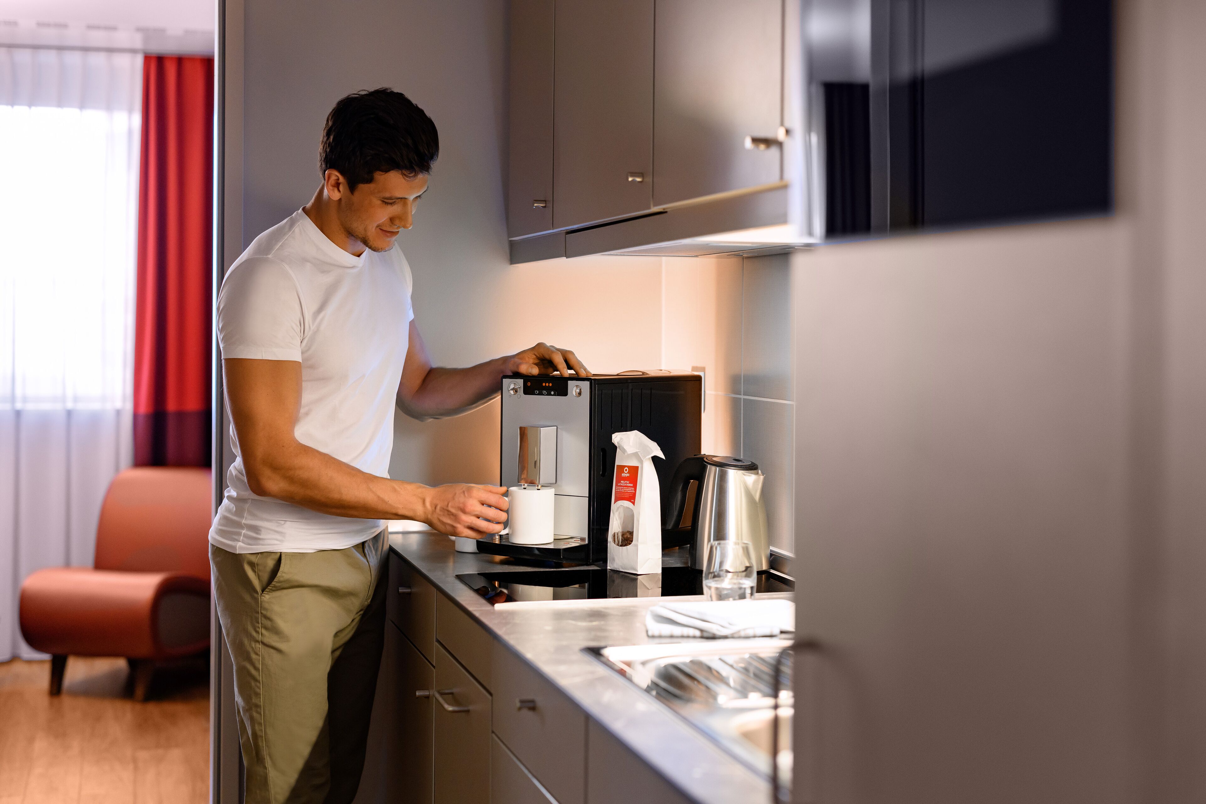 Eine moderne Küche mit Kaffeemaschine, Wasserkocher und einem Glas Wasser auf der Arbeitsfläche.