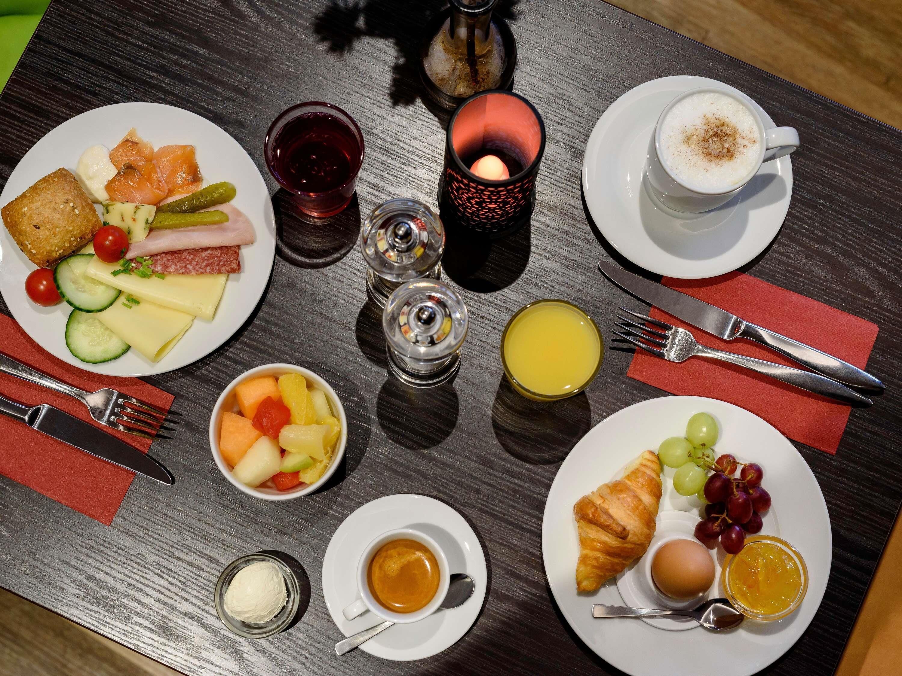 Un desayuno con platos de comida, bebidas y cubiertos sobre una mesa.