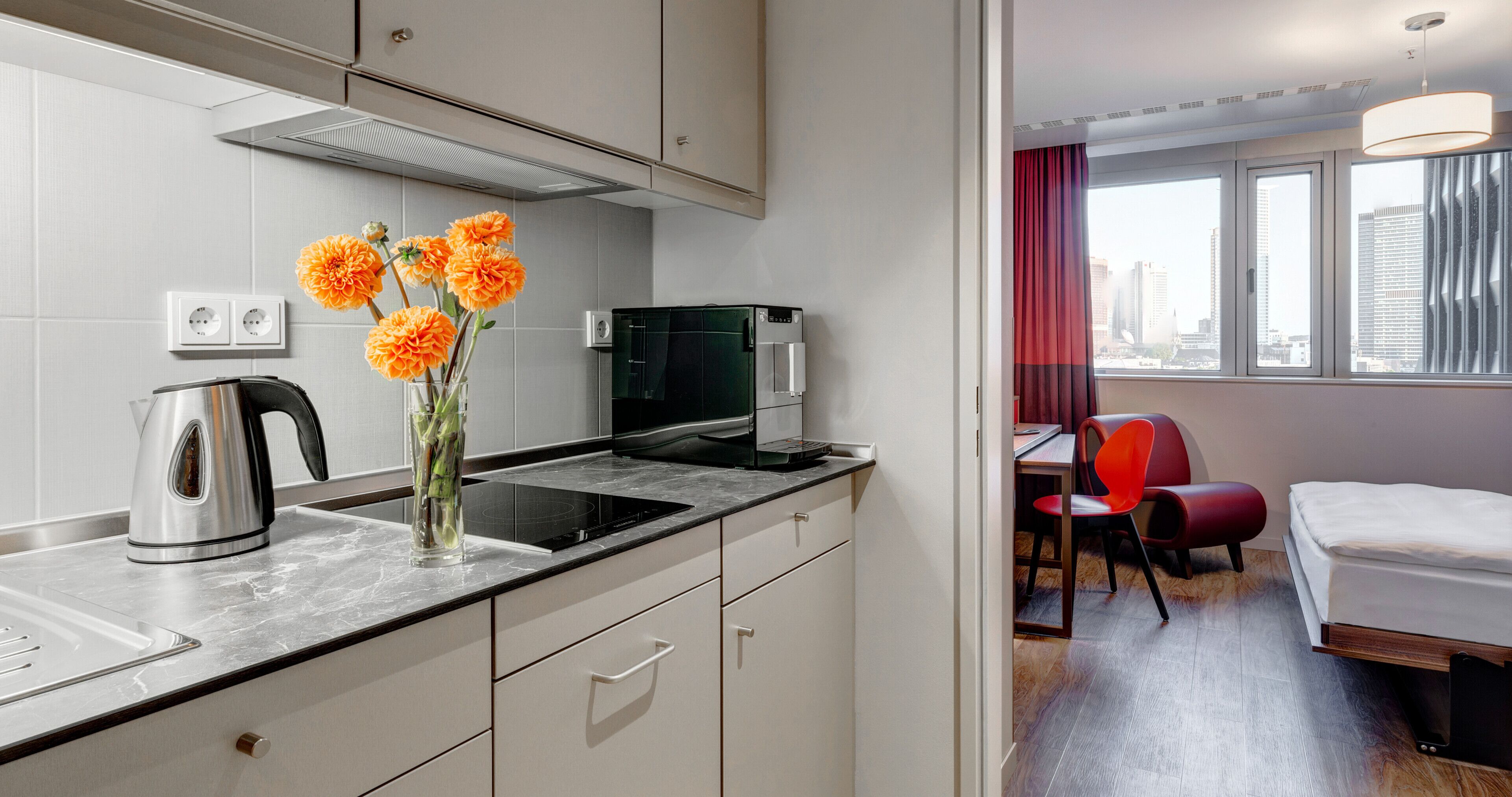 Une cuisine moderne équipée d’une bouilloire, d’une machine à café et d’un vase avec des fleurs.