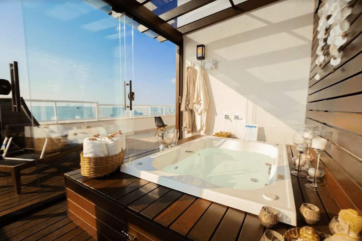 A wooden deck with a hot tub, wicker baskets, and a towel rack.