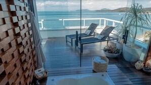 A wooden deck with a hot tub, lounge chairs, and potted plants overlooking the sea. - Hotel VillaReal Sao Francisco do Sul (São Francisco do Sul)