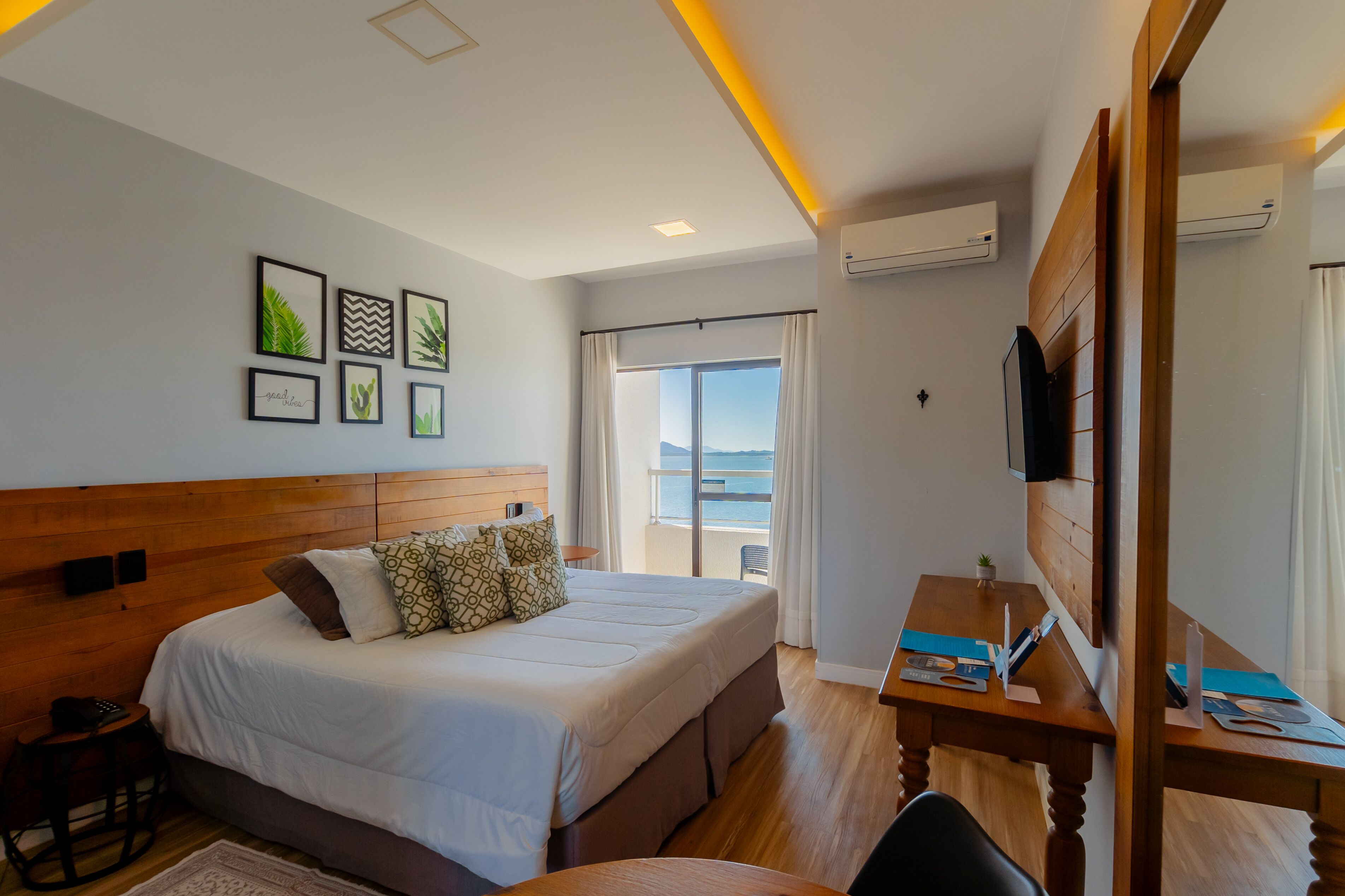 Une chambre d’hôtel avec un lit, un bureau, une chaise, une télévision et un balcon offrant une vue.