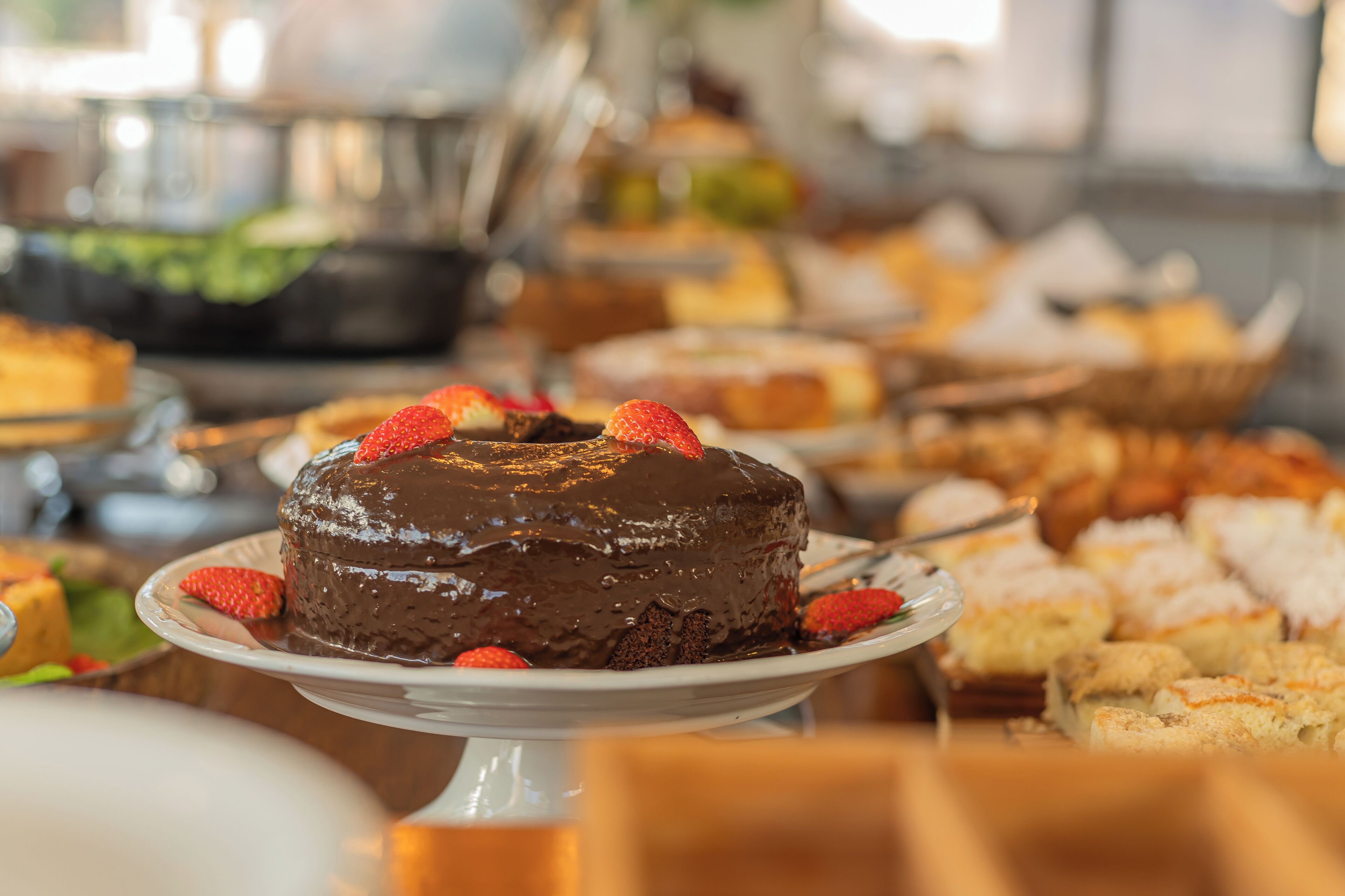 A dessert buffet with a chocolate cake topped with strawberries.