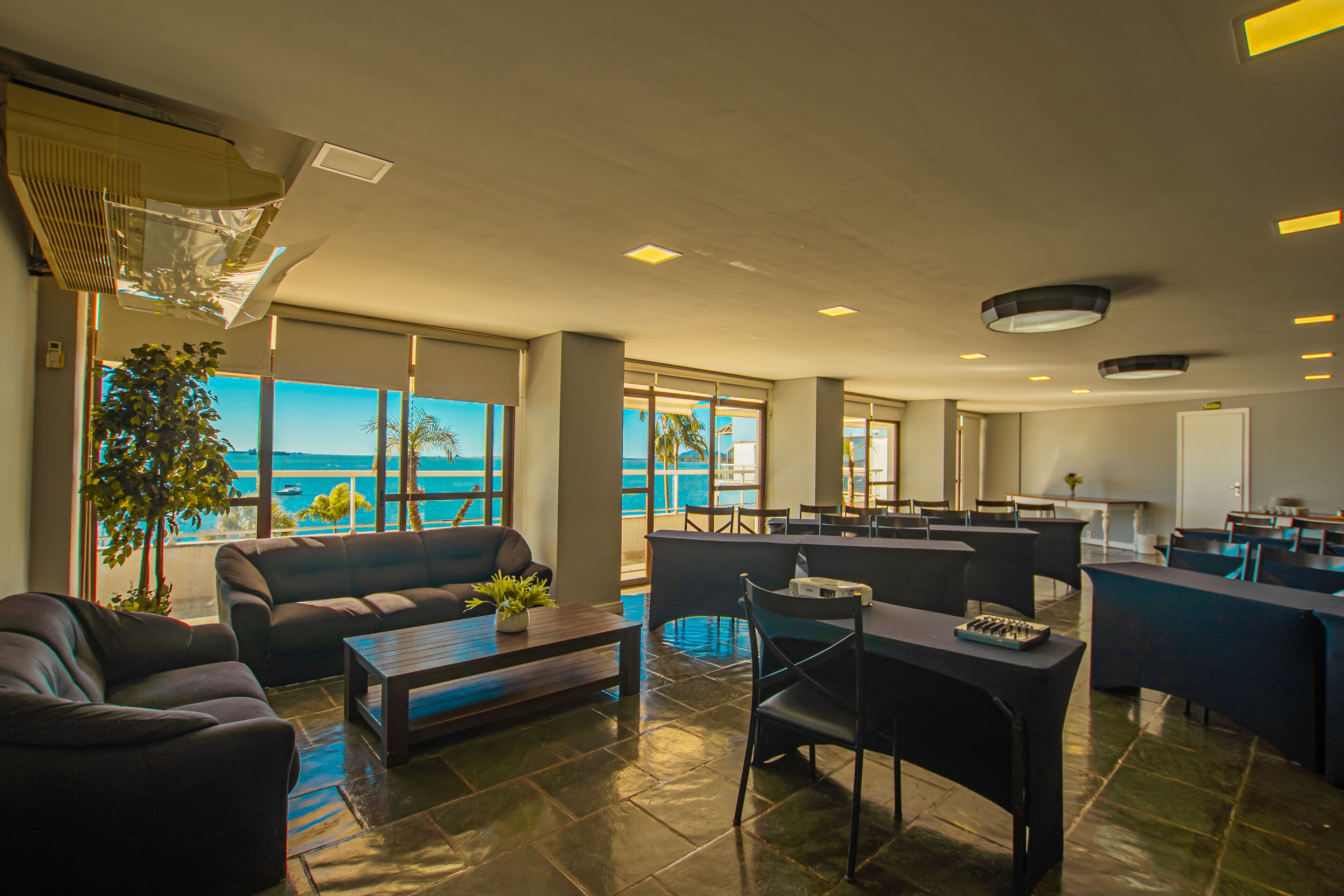 Un moderno vestíbulo de hotel con un amplio espacio de estar, un bar y vistas al océano.