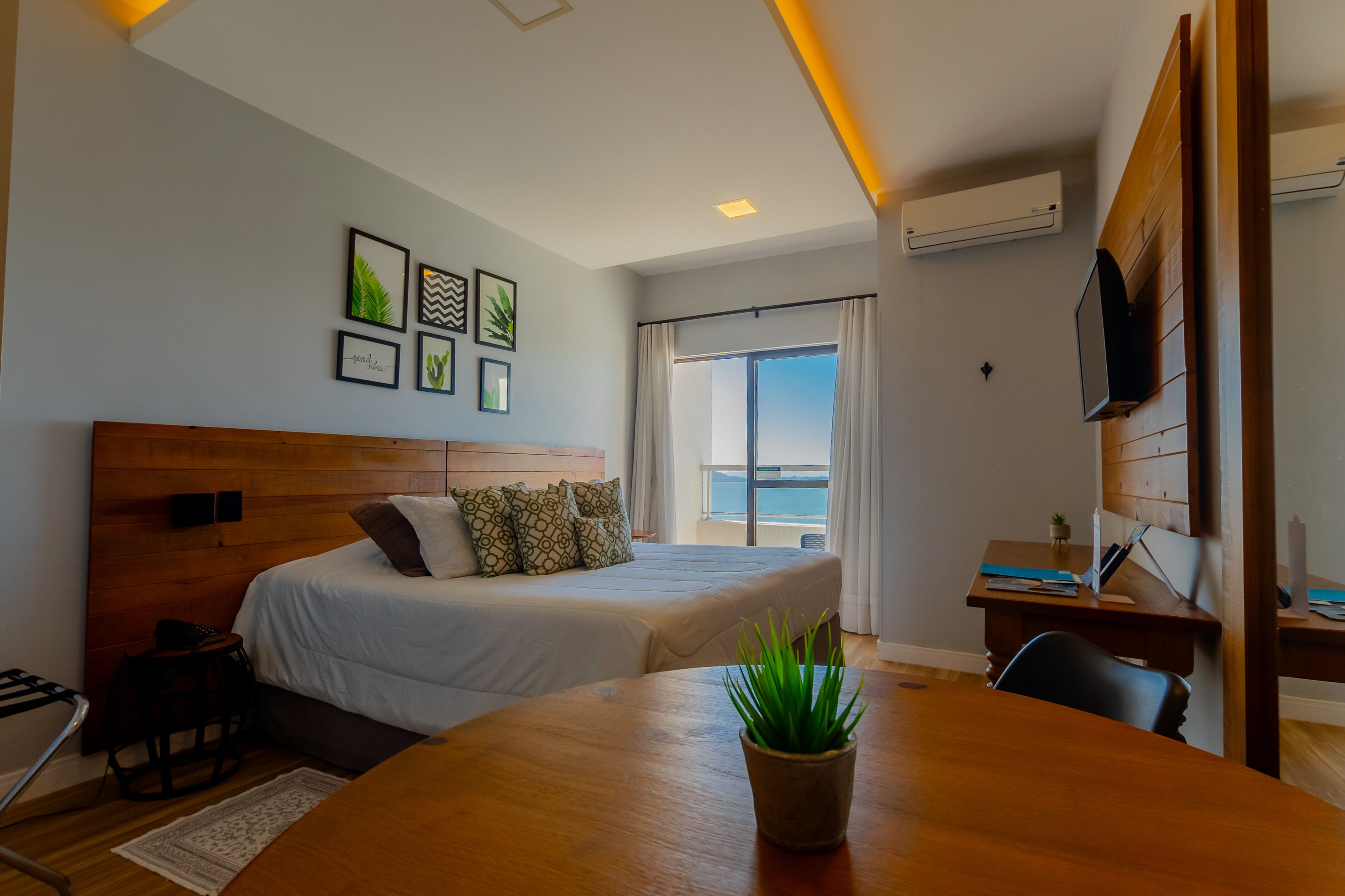 A hotel room with a bed, a desk, a TV, and a balcony with a view.