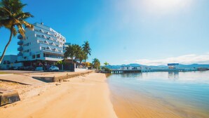 A beachfront hotel with multiple floors, a sandy beach, palm trees, and a calm sea. - Hotel VillaReal Sao Francisco do Sul (São Francisco do Sul)