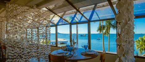 Un comedor con una mesa dispuesta para dos, con vistas al mar a través de amplios ventanales.