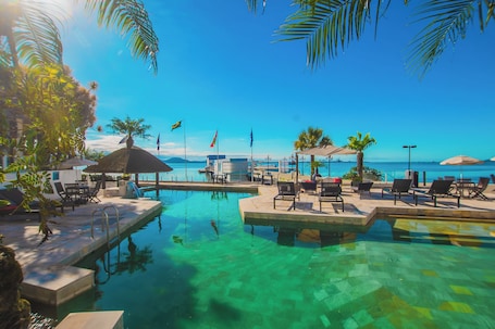 Una piscina techada, una piscina al aire libre, sombrillas