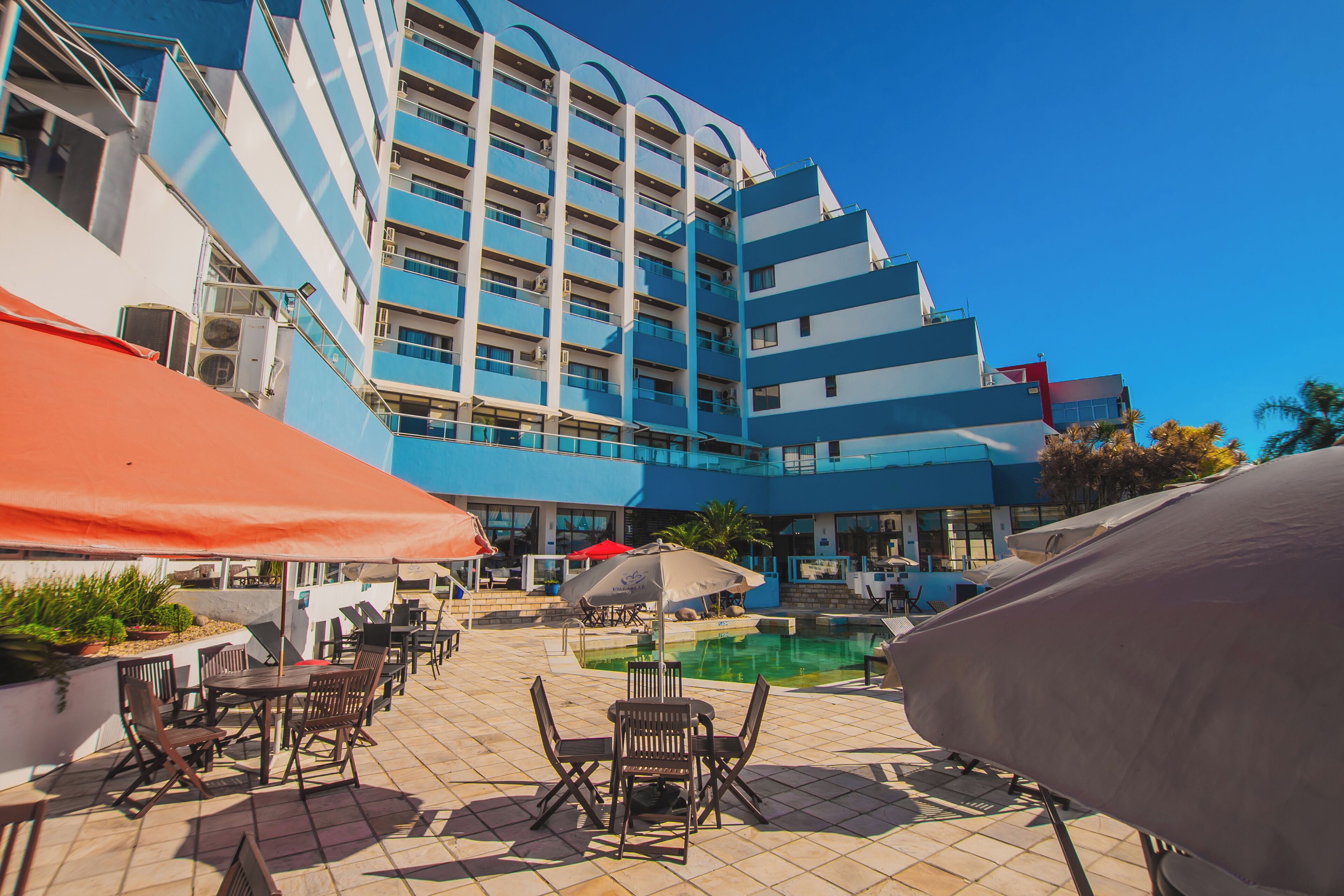 Un hotel con area piscina, posti a sedere all'aperto e un edificio a più piani con balconi.