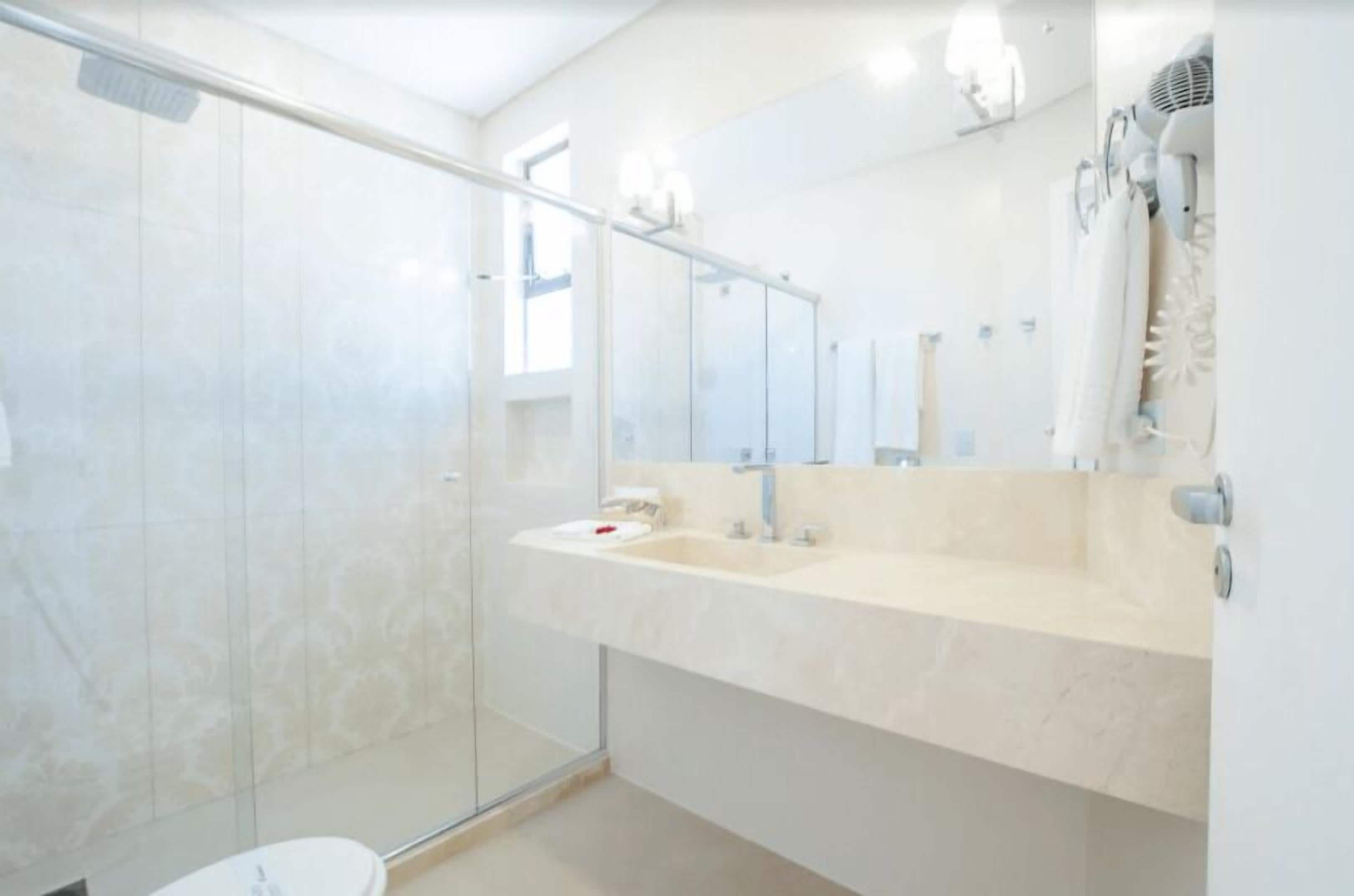A modern bathroom with a glass shower enclosure, a large mirror, and a beige countertop.