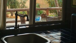 A bathroom with a sink, a window with a view of a rural landscape, and a hanging light fixture.